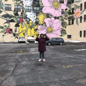 A person standing in front of a colorful mural of flowers.